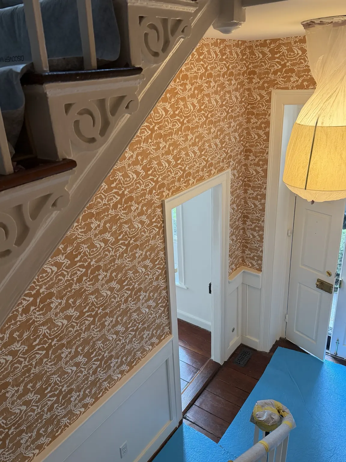 Patterned wallpaper cut around historic stairs doors and paneled wainscoting at 45 Tradd Street Charleston