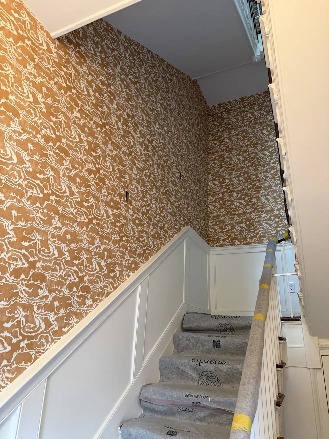 Professional wallpaper pattern matching on a tall stairway wall in a historic Charleston residence
