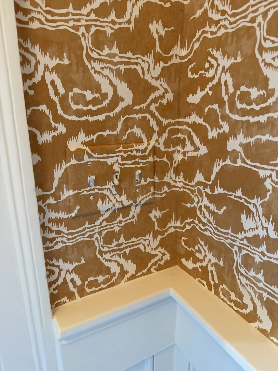 Wallpaper precisely pattern matched across switch plates and an inside corner in Charleston