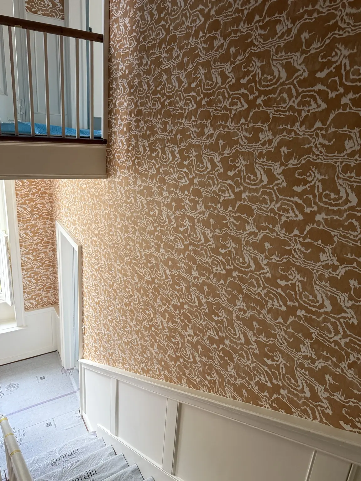 Continuous wallpaper pattern alignment across a tall South of Broad stair hall