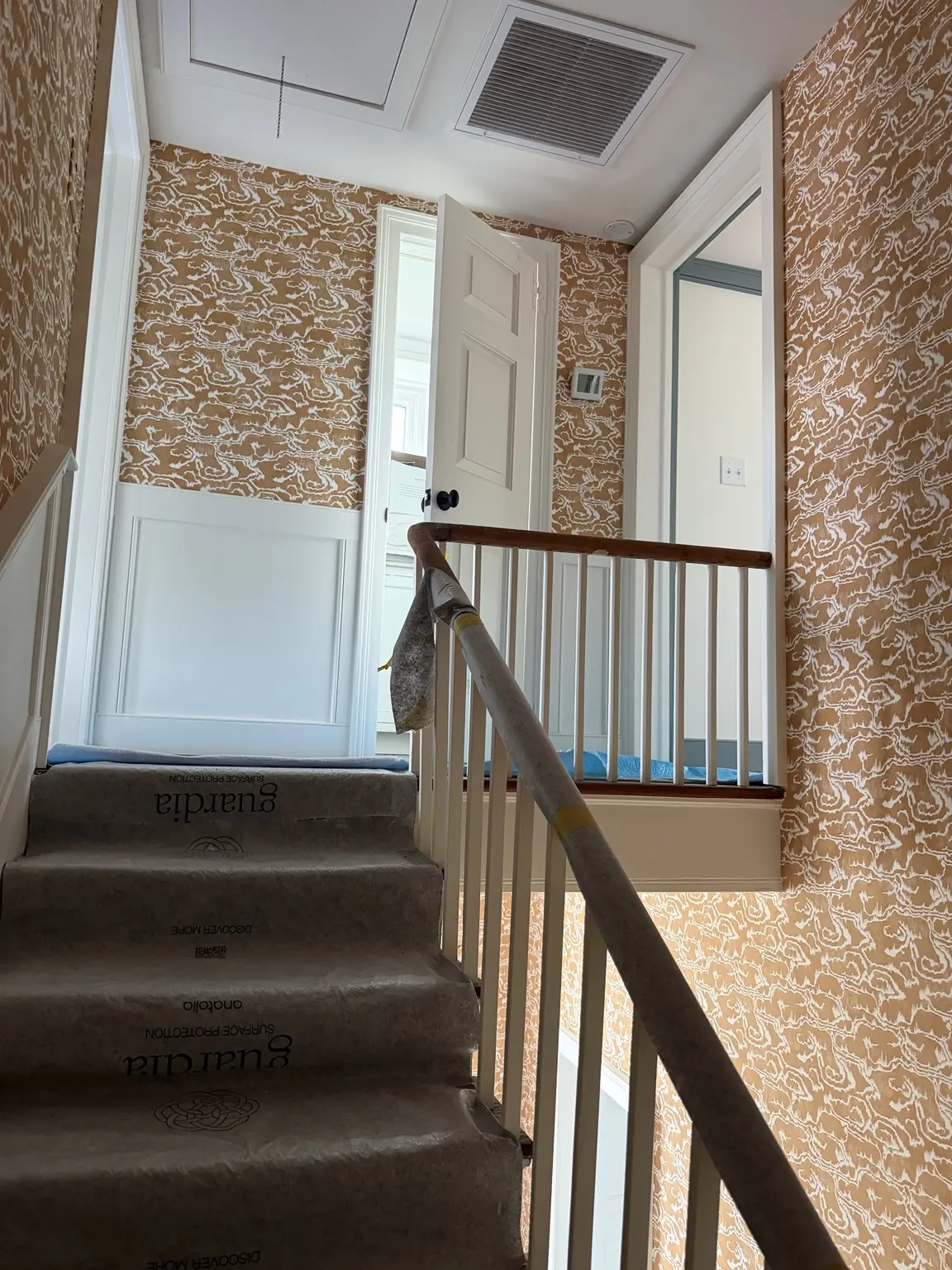 Luxury wallpaper professionally installed around an upper stair landing and historic white millwork