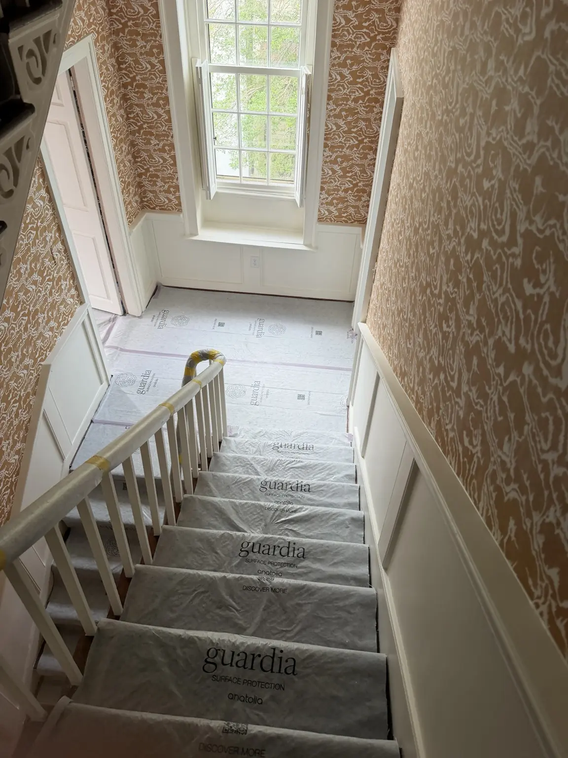 Wallpaper installation surrounding a tall historic window on Tradd Street in Charleston