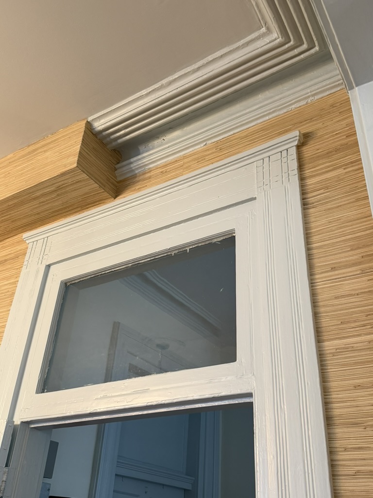 Close detail of hand-cut grasscloth fitted to historic door casing and crown molding